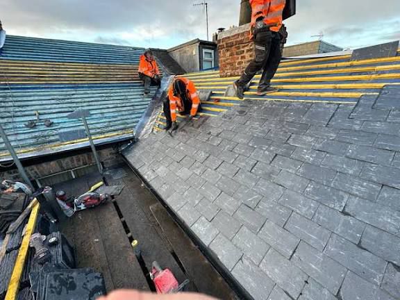Roofers working on slate roof replacement with battens