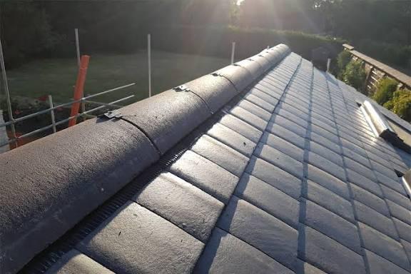 Completed slate roof replacement at sunset with scaffolding