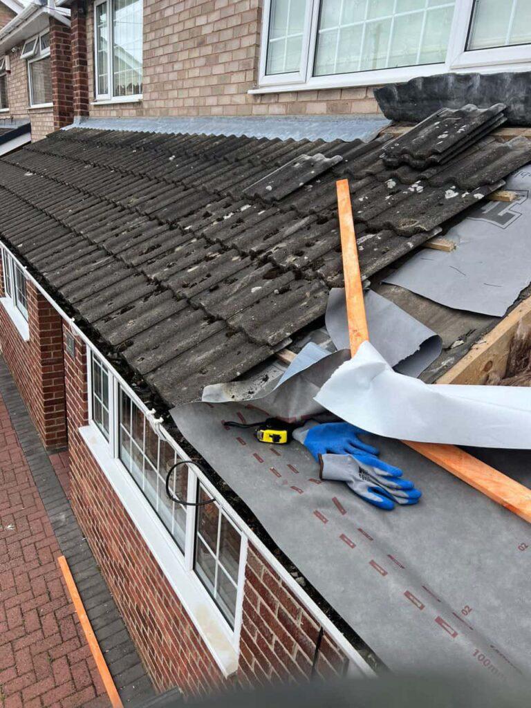 Roofer carrying out emergency roof repair work on damaged tiles in Durham