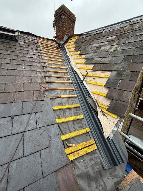Roofer carrying out emergency roof repair work on damaged tiles in Durham