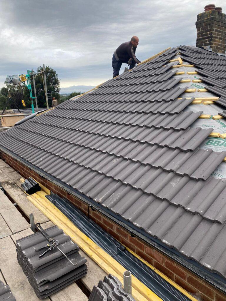 New concrete roof tiles being fitted during a full roof replacement in County Durham